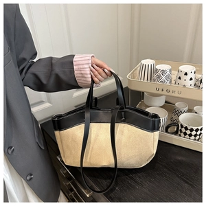 Detail of minimalist beige suede tote bag with black leather straps and contrast trim
