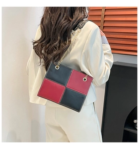 Détail du sac damier rouge et noir avec coutures blanches et bandoulière chaîne dorée