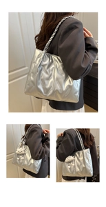 Detail of silver tote bag with pleated texture and twisted rope handle including cloud charm