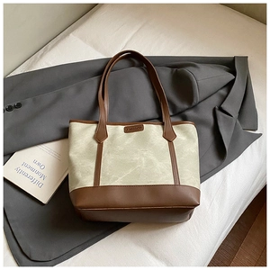 Detail of a vintage two-tone tote bag featuring a Fashion leather label on a grey blazer
