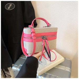 Detail of canvas and pink leather contrast bag with dual zippers and long tassels