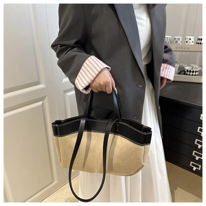 Detail of two-tone tote bag with contrast stitching and suede-textured bottom on a model