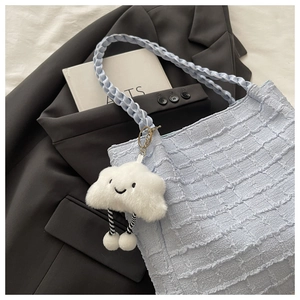 Détail du sac cabas plissé bleu clair avec poignée tressée et breloque nuage en peluche