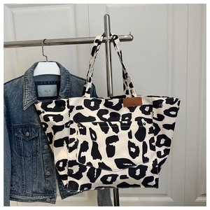 Close-up of leopard print canvas tote bag with front pocket and brown leather patch detail
