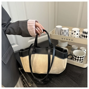 Close-up of beige canvas and black leather tote bag with stylish contrast stitching