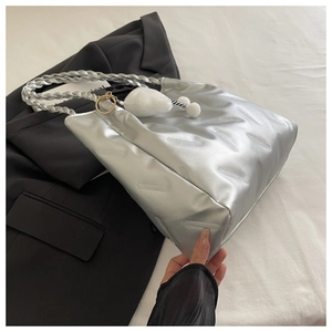 Detail of silver metallic handbag with textured diagonal lines and plush white charm