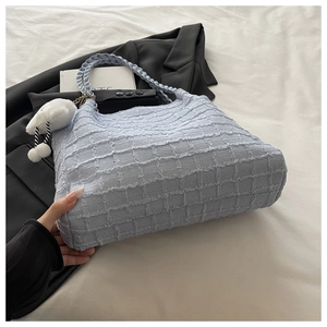 Détail du sac cabas bleu clair à texture gaufrée avec pendentif pelucheux élégant