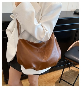 Close-up of brown pleated leather hobo bag with a soft texture and rectangle logo