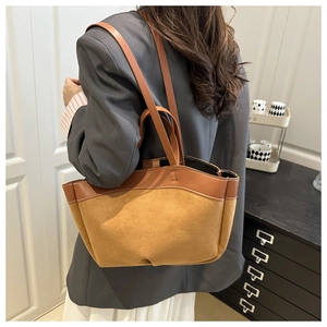 Brown suede and leather tote bag shown worn as a crossbody on a stylish model