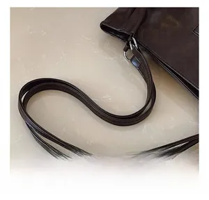 Detailed macro view of the dark brown leather handle and silver metal hardware of this tote