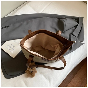Top-down detail of off-white canvas tote bag showing zipper closure and large inner compartment