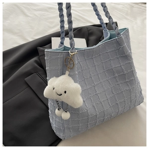Détail du sac à main bleu clair à carreaux avec un pendentif nuage en peluche blanche