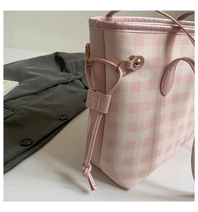 Detailed view of pink plaid canvas tote bag with side drawstring and golden hardware