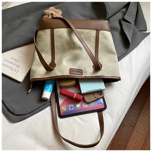 Spacious canvas and brown leather tote bag showing internal storage for tablet and phone