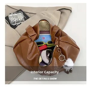 Brown soft leather bag interior showing capacity for sunglasses and cosmetics with charm