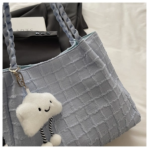 Détail du sac cabas bleu clair à texture gaufrée avec pendentif nuage en peluche