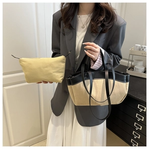 Detail of khaki canvas tote bag with black leather trim and matching zipper pouch