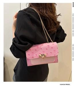 Close-up of pink crossbody bag featuring floral bow patterns and gold chain strap