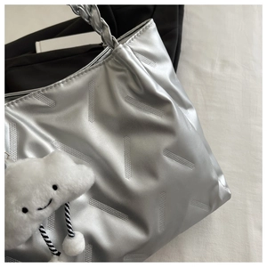 Close-up of silver tote bag with striped texture and white cloud plush charm