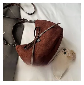Detail of brown suede crescent bag with bow decoration and smooth leather strap