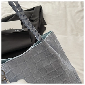 Détail du sac à main bleu clair en tissu gaufré avec pendentif en forme de pompon doux