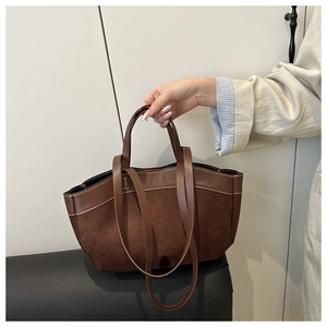 Detail of brown suede tote bag with contrast stitching and versatile shoulder straps