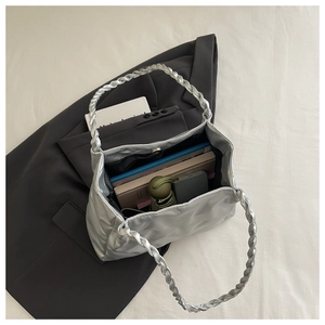 Macro detail of silver quilted tote bag showing woven handles and spacious inner capacity