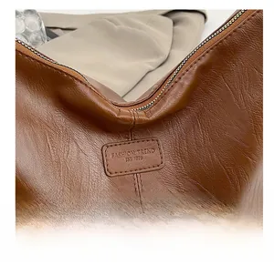 Detail view of brown pebbled leather texture and fashion trend embossed label on tote bag