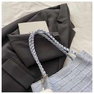 Détail du sac cabas bleu clair avec texture à carreaux, anse tressée et pompon blanc