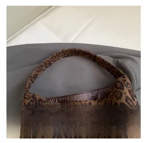 Detail showing the comfortable handle and textured leopard print fabric of the bucket bag