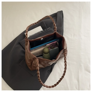 Macro detail of large capacity brown leather tote bag with braided handle and spacious interior