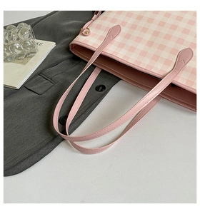 Close-up of pink checkered tote bag with leather strap and golden hardware accents