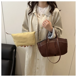 Close-up of contrast stitching on a brown suede tote bag and yellow canvas pouch detail
