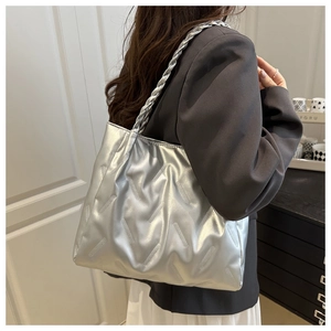 Detail of silver metallic tote bag featuring quilted texture and braided handle