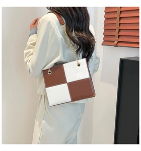 Mannequin portant un sac carré à carreaux marron et blanc avec chaîne dorée