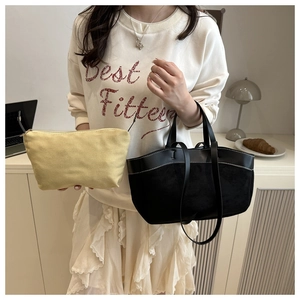 Detail view of black tote bag and yellow inner pouch in a modern lifestyle setting