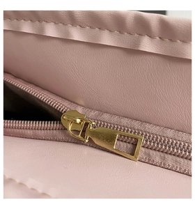 Close-up of golden zipper on pink litchi texture leather underarm bag detail