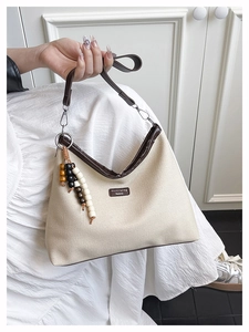 Detail of beige canvas tote with brown leather trim and bohemian beaded charm