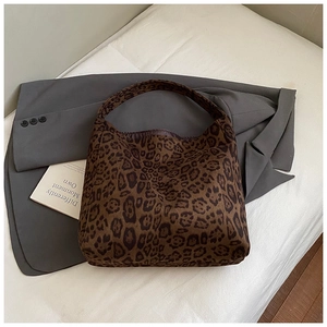 Flat lay of a leopard print tote bag on white fabric with a blazer and book detail