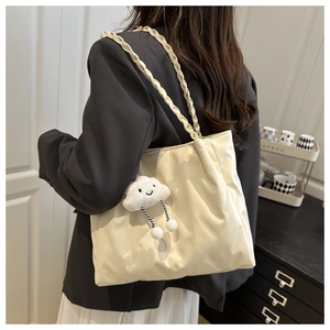 Close-up of quilted cream tote bag with woven handles and a cute cloud charm detail