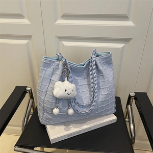 Sac fourre-tout en tweed bleu clair avec anses tressées et charme nuage sur une chaise