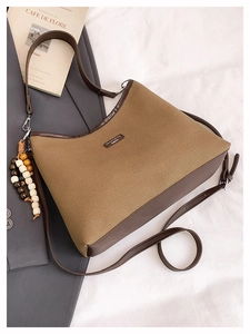 Detail of canvas bucket bag with wooden bead tassel and metal plate on white fabric