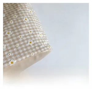 Detail of floral embroidery on gingham canvas tote bag with smooth faux leather bottom