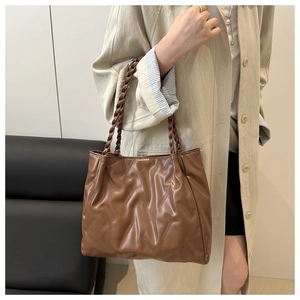 Detail of brown pleated tote bag with woven handles and textured synthetic leather
