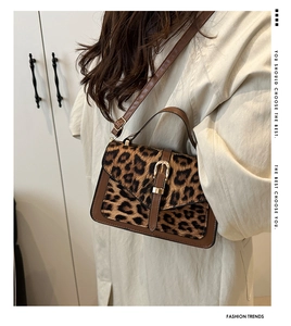 Leopard print crossbody bag with metal buckle and leather strap on model in neutral room
