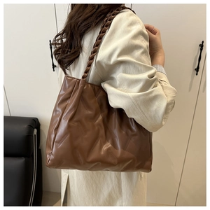 Detail of vintage brown leather tote bag featuring woven straps and diagonal textures