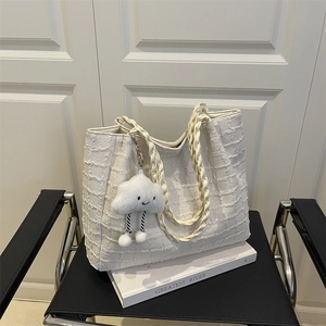 Sac fourre-tout texturé blanc avec poignée en soie et charme nuage sur une chaise