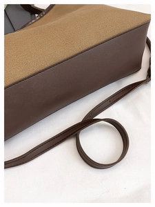 Detailed close-up of beige canvas and dark brown leather trim with fine stitching