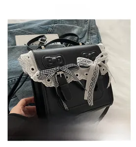 Dettaglio borsa nera in ecopelle con pizzo bianco e decorazione con fiocco a quadri