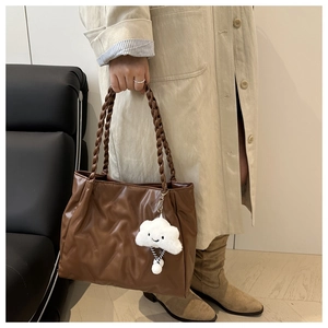 Brown quilted tote bag with braided handles and cloud plush charm detail in indoor setting